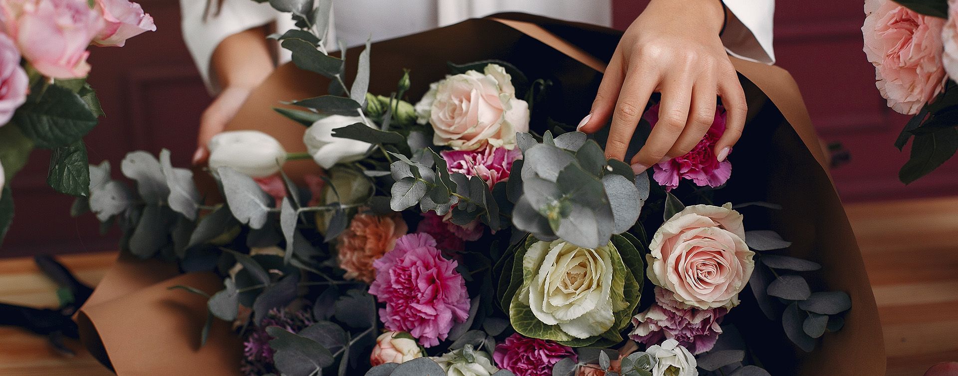 Une personne compose un bouquet de fleurs colorées, avec des fleurs blanc et rose.