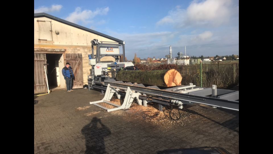 Baumstamm wird mit einer Maschine zu Brennholz verarbeitet