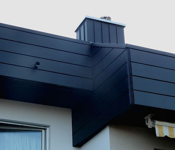 Ein schwarzes Dach mit einem Schornstein darauf