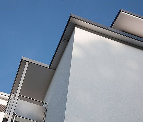 Blick nach oben auf ein Gebäude mit Balkonen und einem blauen Himmel im Hintergrund