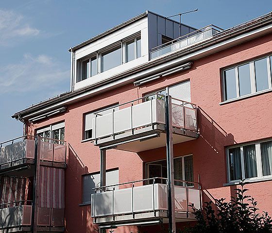 Ein rosa Wohnhaus mit Balkonen und Fenstern