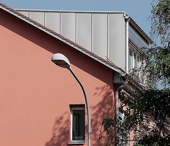Ein rosa Gebäude mit einem weißen Dach und einer Straßenlaterne