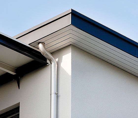 Ein weißes Haus mit blauem Dach und Dachrinnen