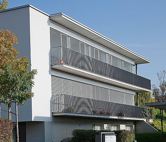 Ein großes weißes Gebäude mit einem Balkon und einem Zaun