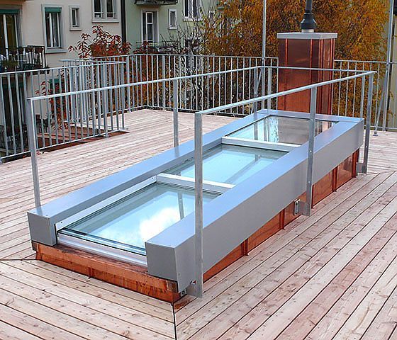 Ein Holzdeck mit Metallgeländer und Kupferkamin