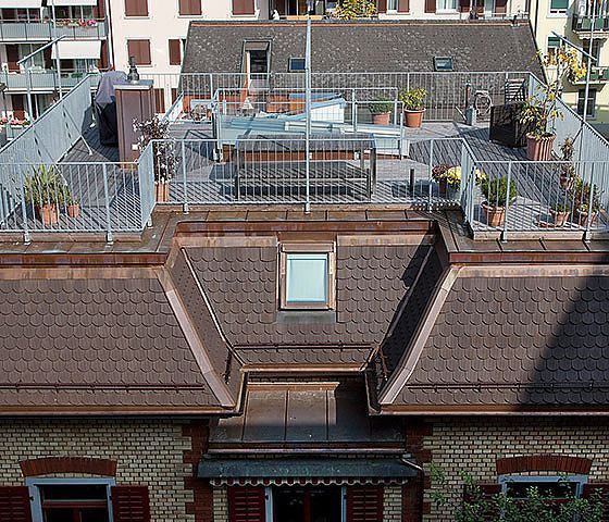 Das Dach eines Gebäudes hat einen Balkon mit Pflanzen darauf