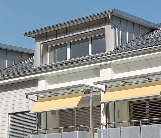 Ein Haus mit einem Balkon mit einer gelben Markise darauf