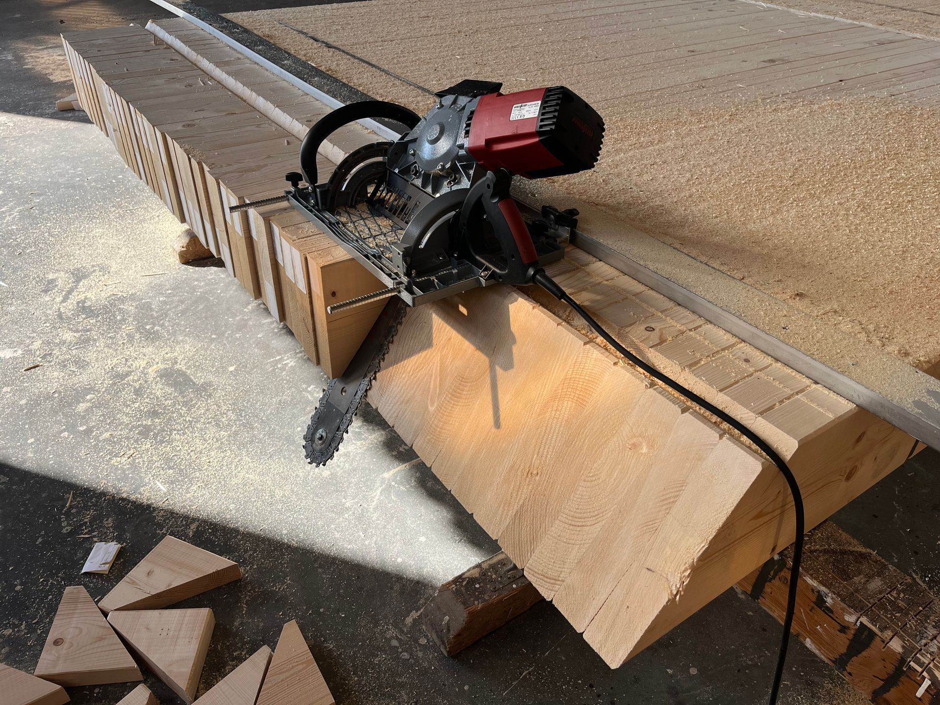 Ein Tischler in einer Werkstatt bearbeitet eine Holzplatte mit einem Hobel