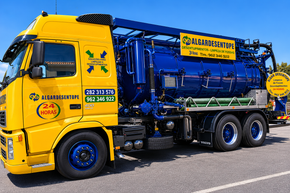 Desentupimentos Pessoa em corda na borda de um grande tanque de concreto, com maquinário azul-amarelo e escada por perto.