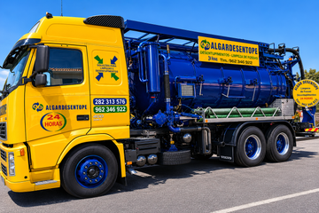 Desentupimentos Pessoa em corda na borda de um grande tanque de concreto, com maquinário azul-amarelo e escada por perto.