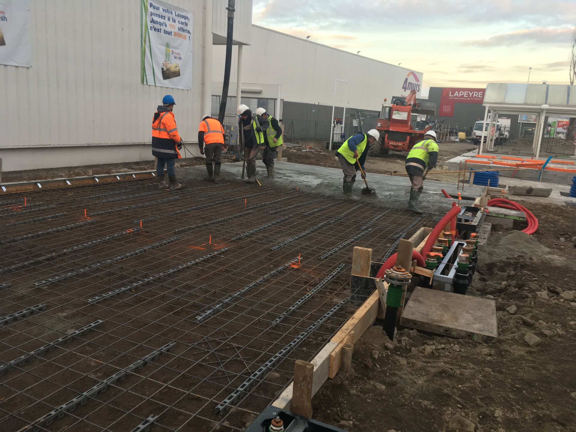 Des ouvriers du bâtiment coulent du béton sur une armature en fer à béton, près d'un bâtiment.