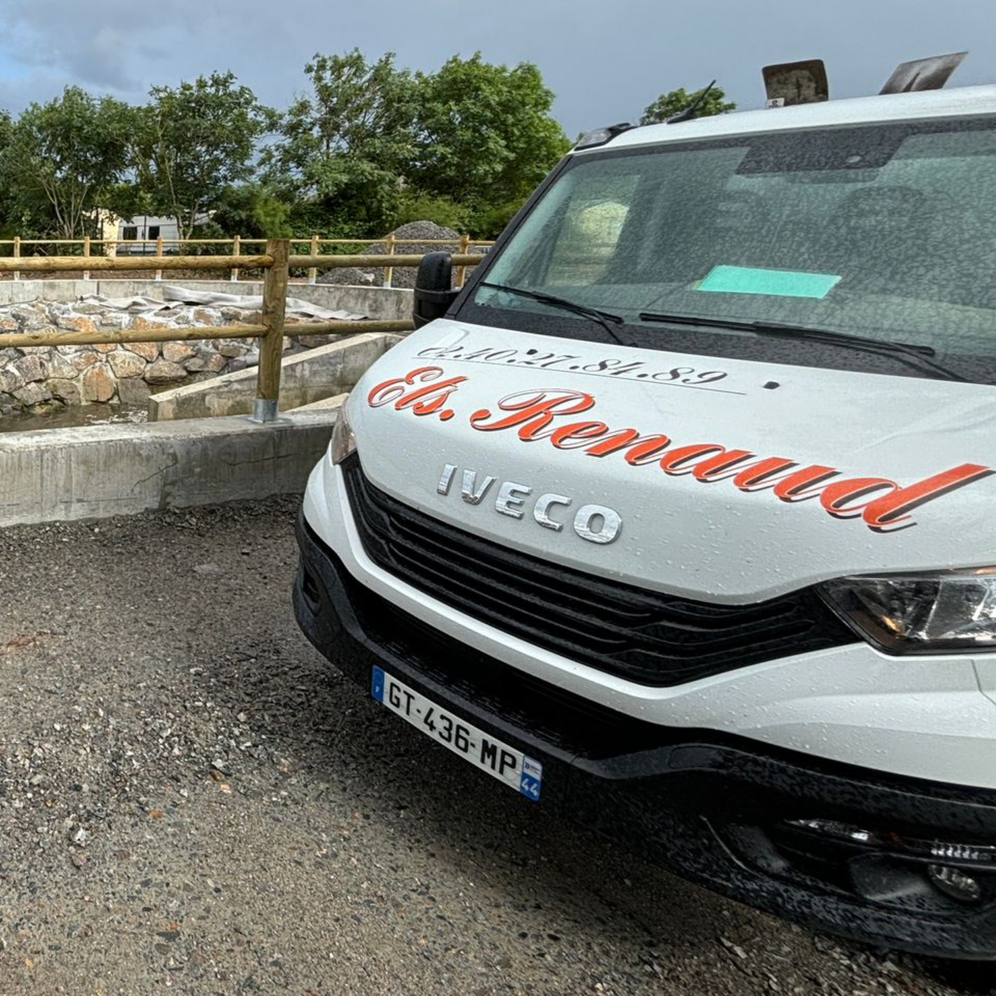 Fourgon blanc avec logo A. Renaud stationné à l'extérieur ; structure en pierre en arrière-plan.