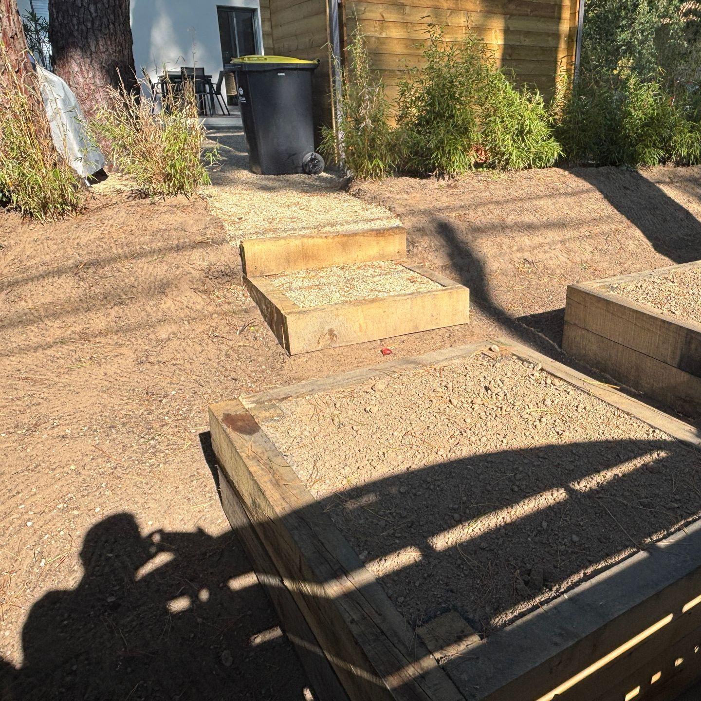 Des marches et des parterres de gravier bordés de bois se dressent dans une cour brune.