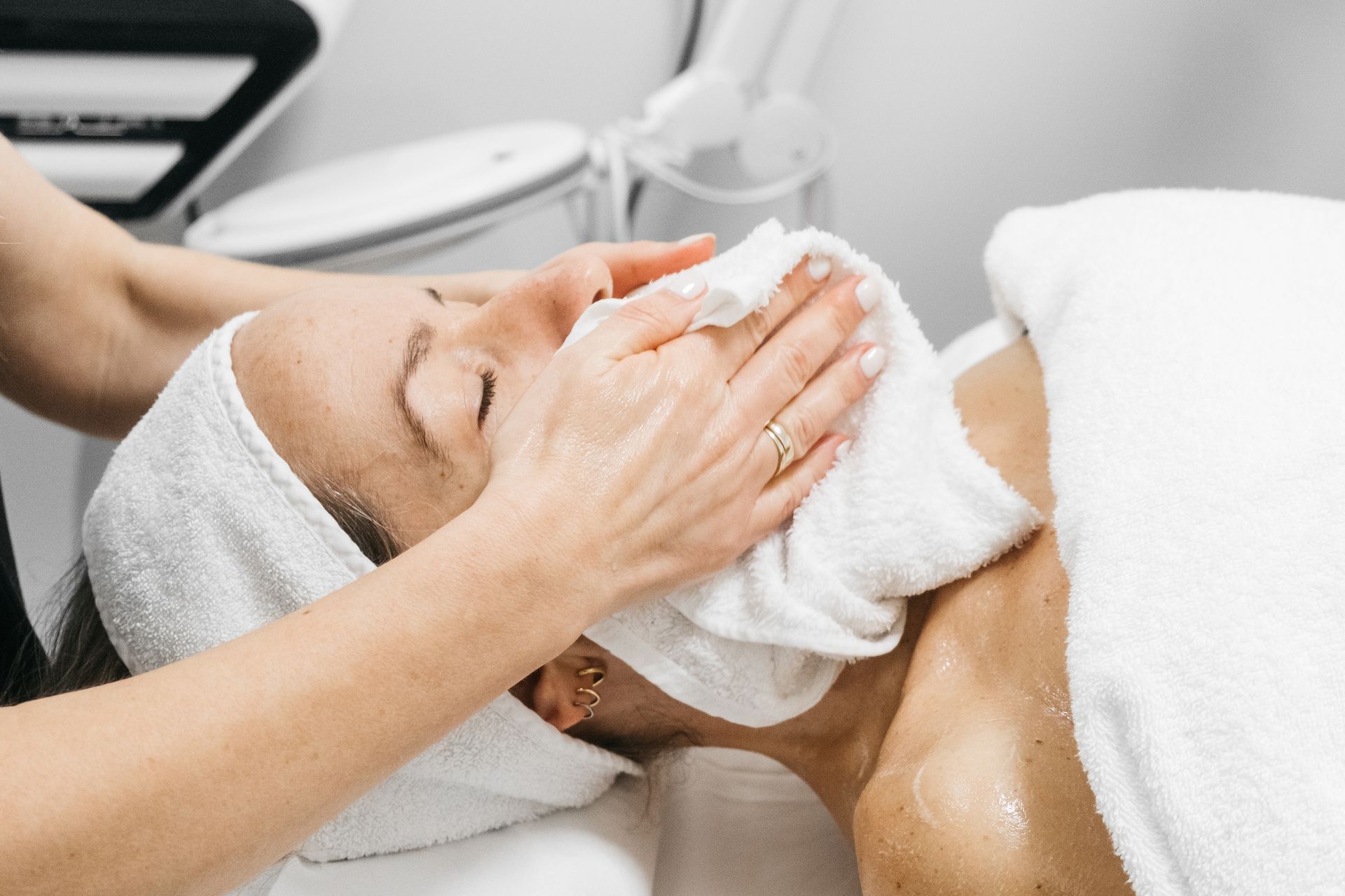 Donna che riceve un trattamento viso, coperta da un asciugamano, in una spa.