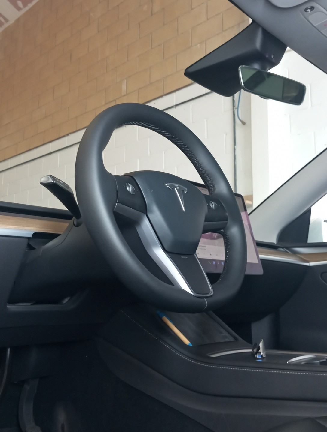 Interior de un coche Tesla con volante y consola central, visto desde el asiento del conductor.