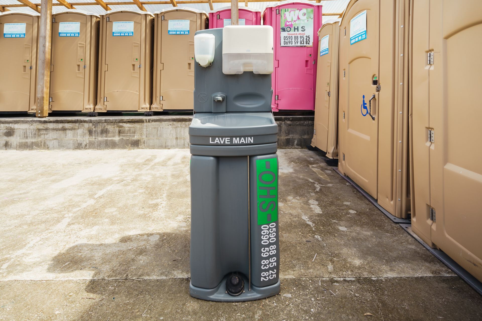 Station de lavage des mains portable devant des toilettes portables sur un site extérieur