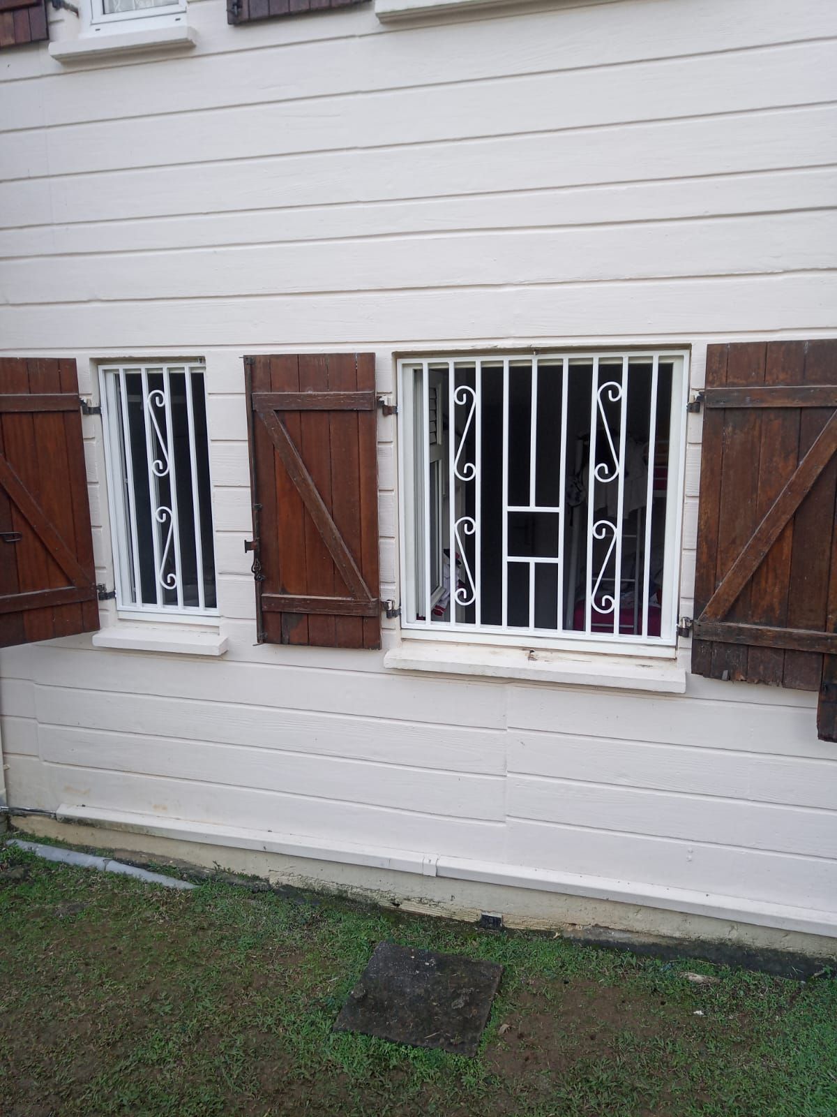 Deux fenêtres à cadre blanc avec grilles de sécurité en métal.