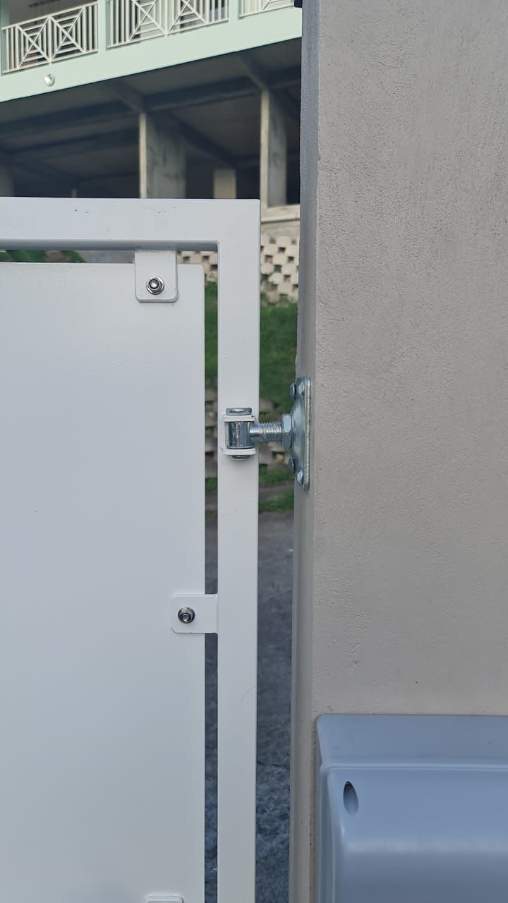 Vue latérale d'une charnière de portail en métal blanc.