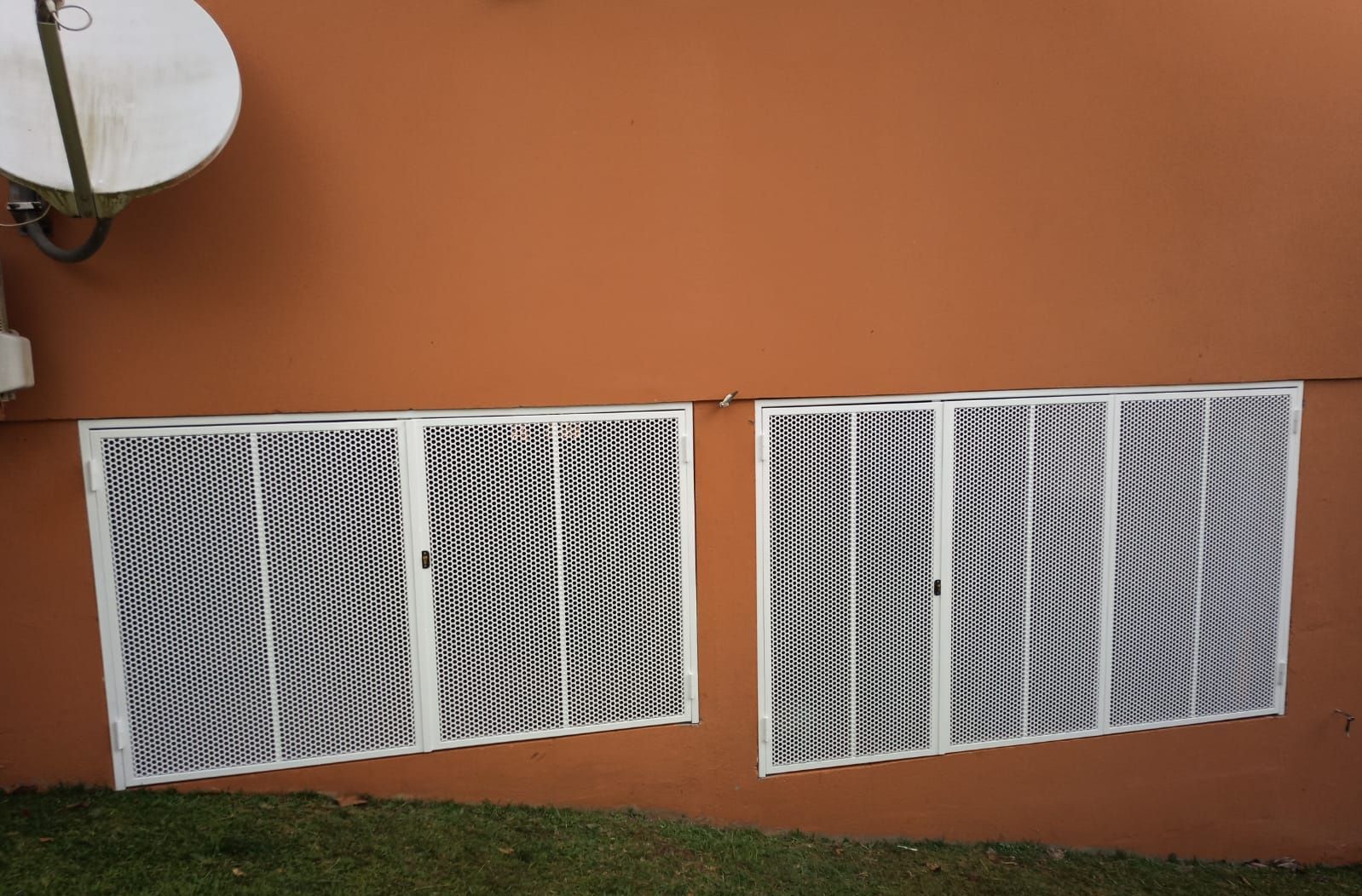 Deux grilles de sécurité en métal blanc pour fenêtres.