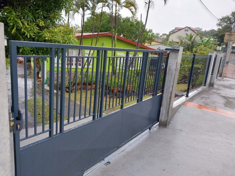 Un portail coulissant moderne en métal gris foncé, avec des barreaux verticaux.