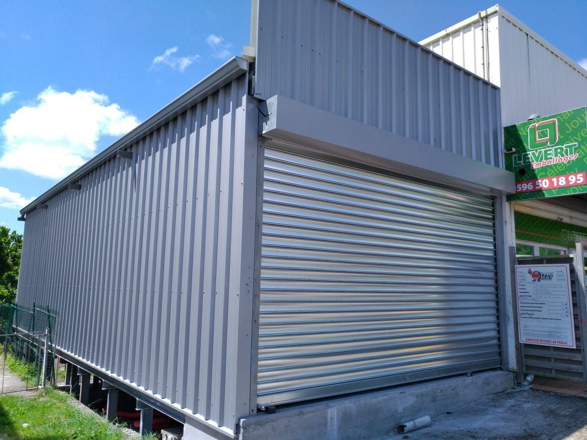 Une porte de garage métallique blanche à quatre panneaux avec une grille supérieure en losanges.