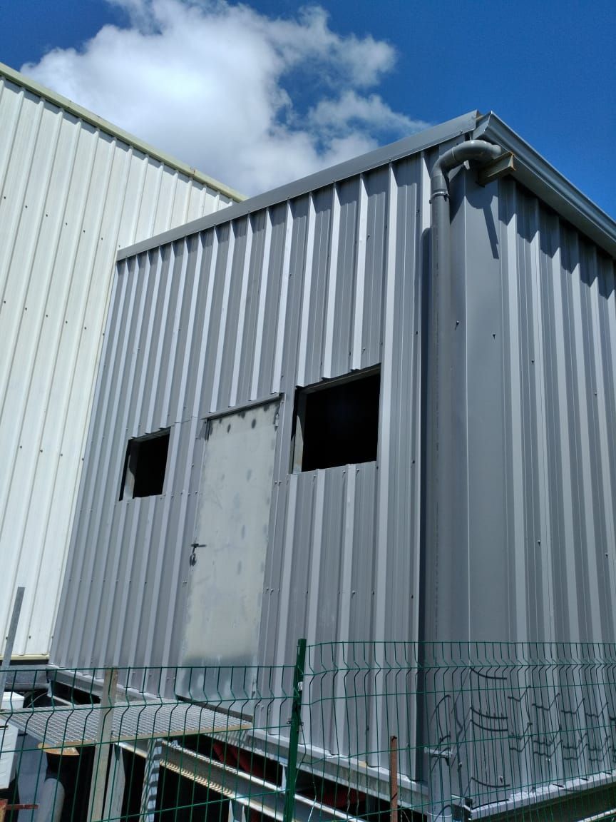 Un petit local en tôle ondulée grise.