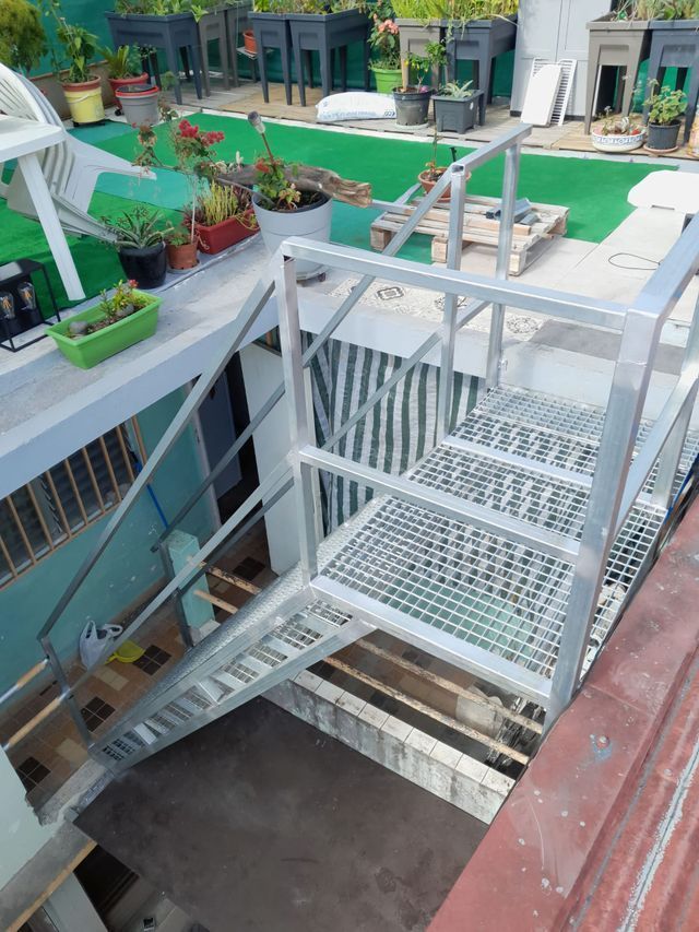 Un escalier métallique avec palier et rampe.