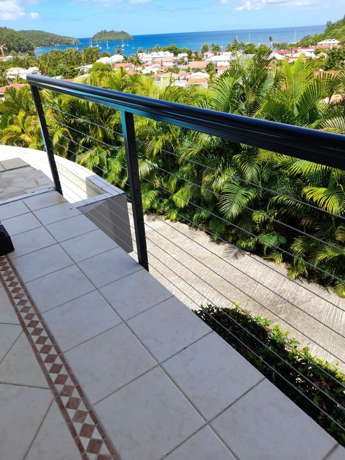 Un balcon carrelé avec une balustrade noire en métal.