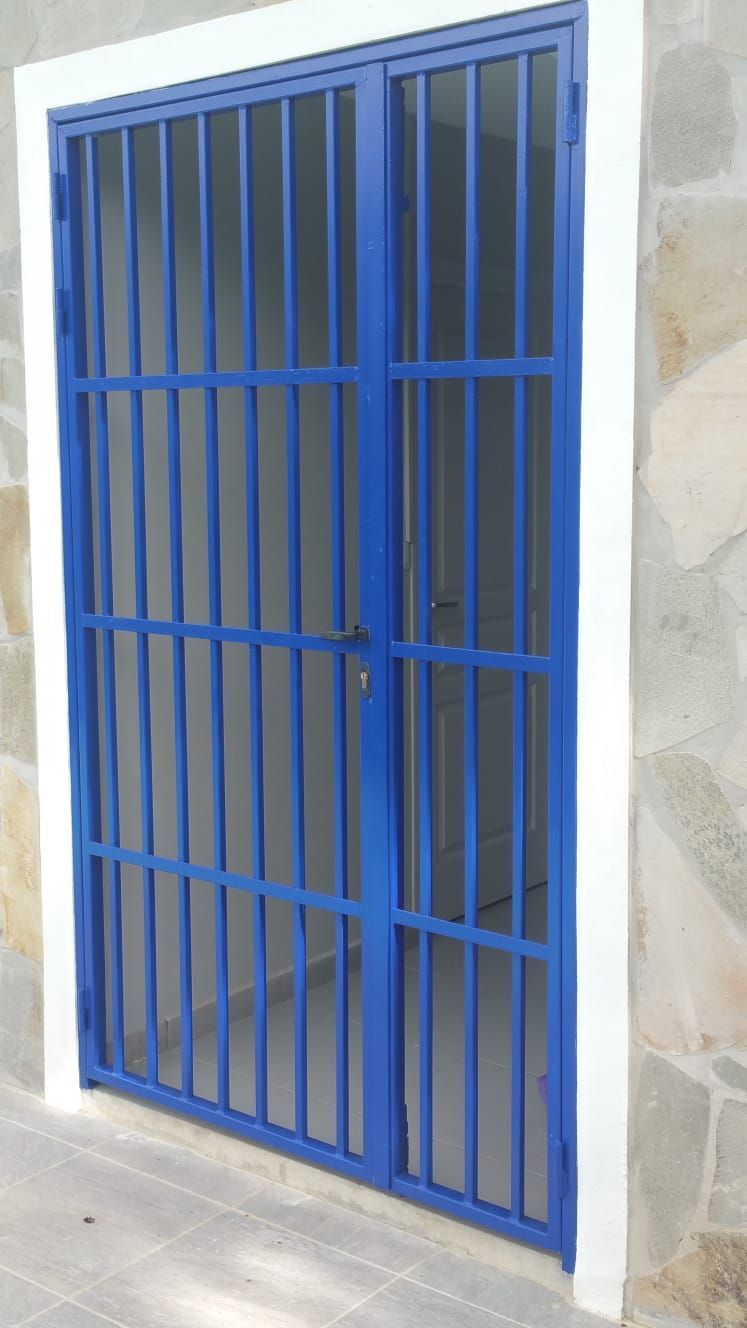 Une grille de protection en métal bleu à barreaux verticaux.