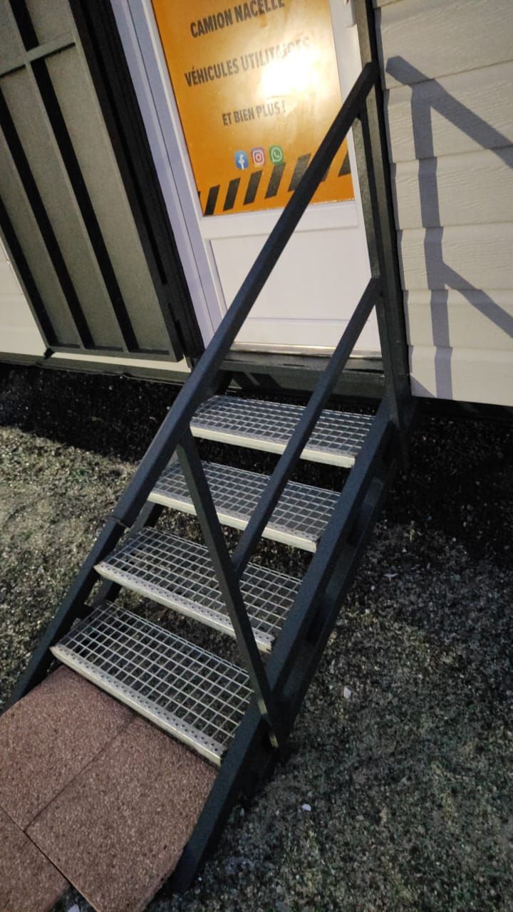 Un escalier métallique gris foncé à marches grillagées.