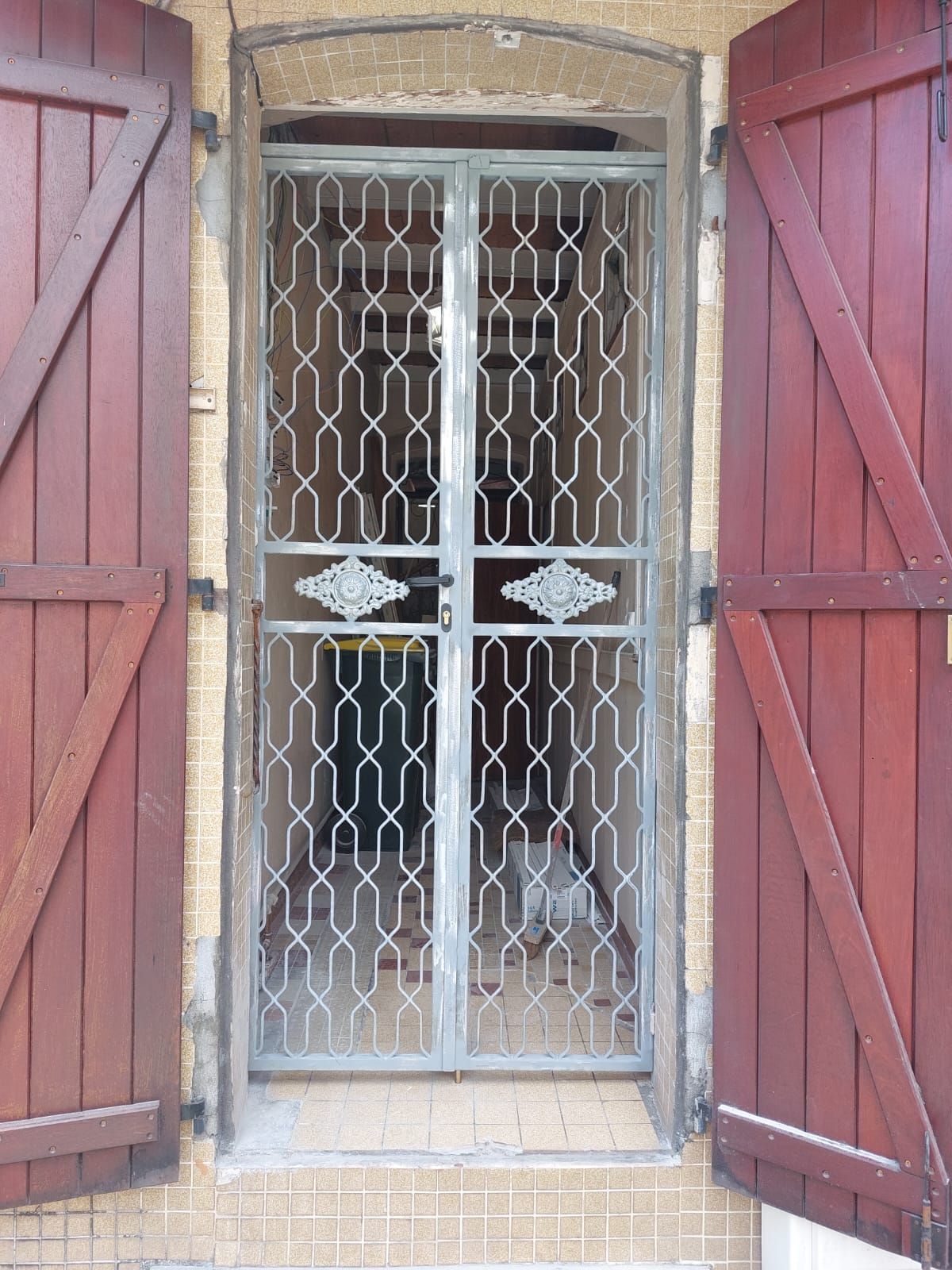 Une grille de sécurité en métal argenté se dresse dans l'embrasure d'une porte.