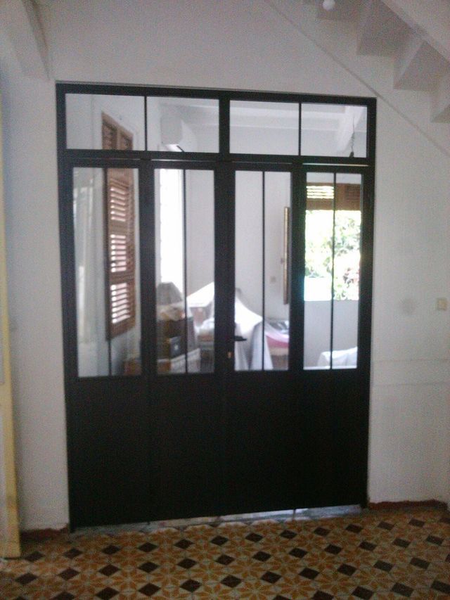 Une porte intérieure noire à plusieurs panneaux en métal et en verre.