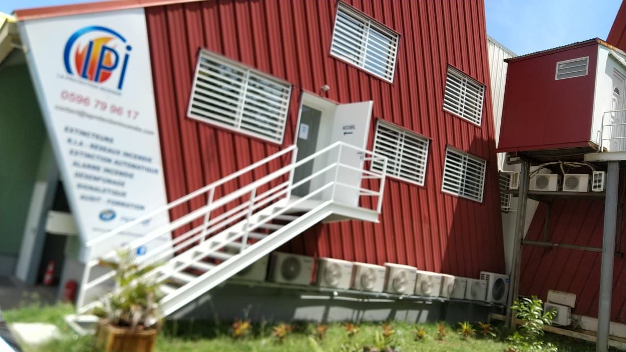 Un bâtiment commercial rouge avec un escalier extérieur en métal blanc.