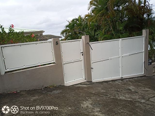 Un portillon piéton en métal blanc et un portail pour allée carrossable.