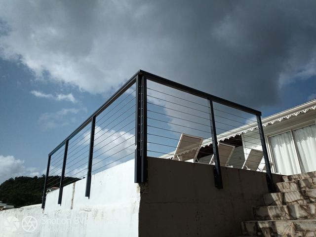 Une rambarde en câble métallique noir entoure une terrasse surélevée.