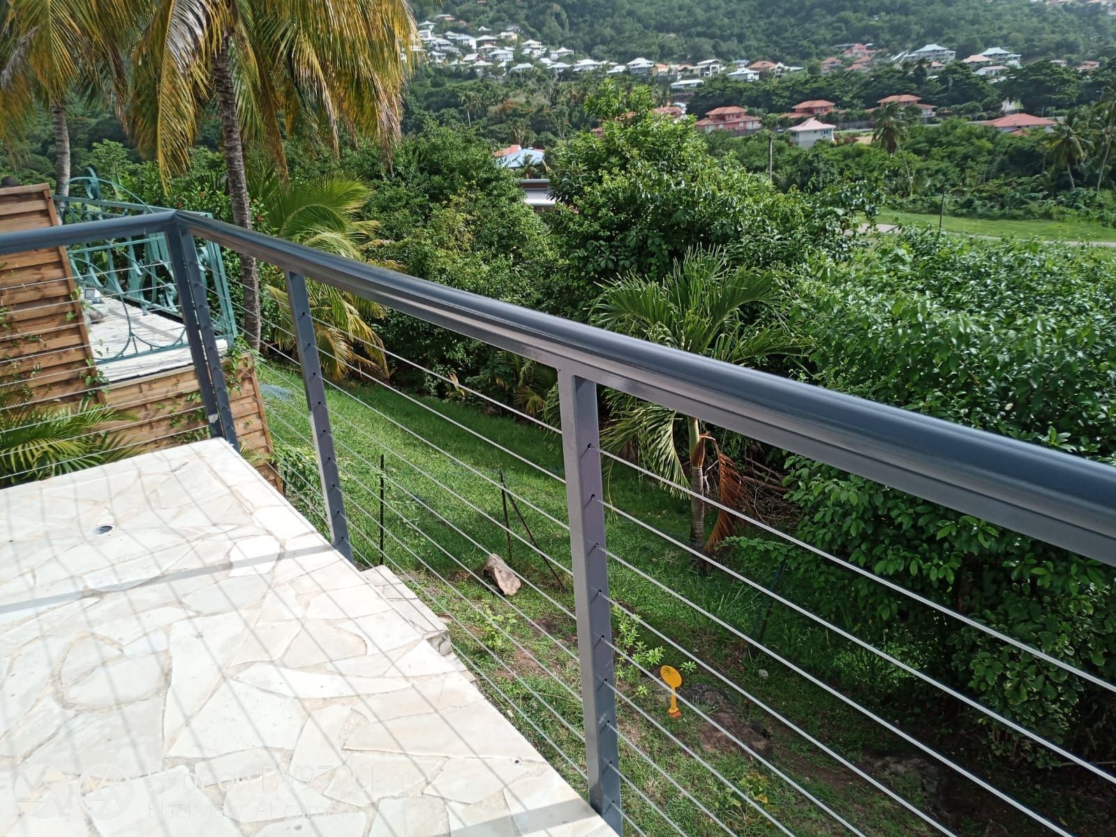 Une balustrade de balcon en métal, composée de fins fils horizontaux.