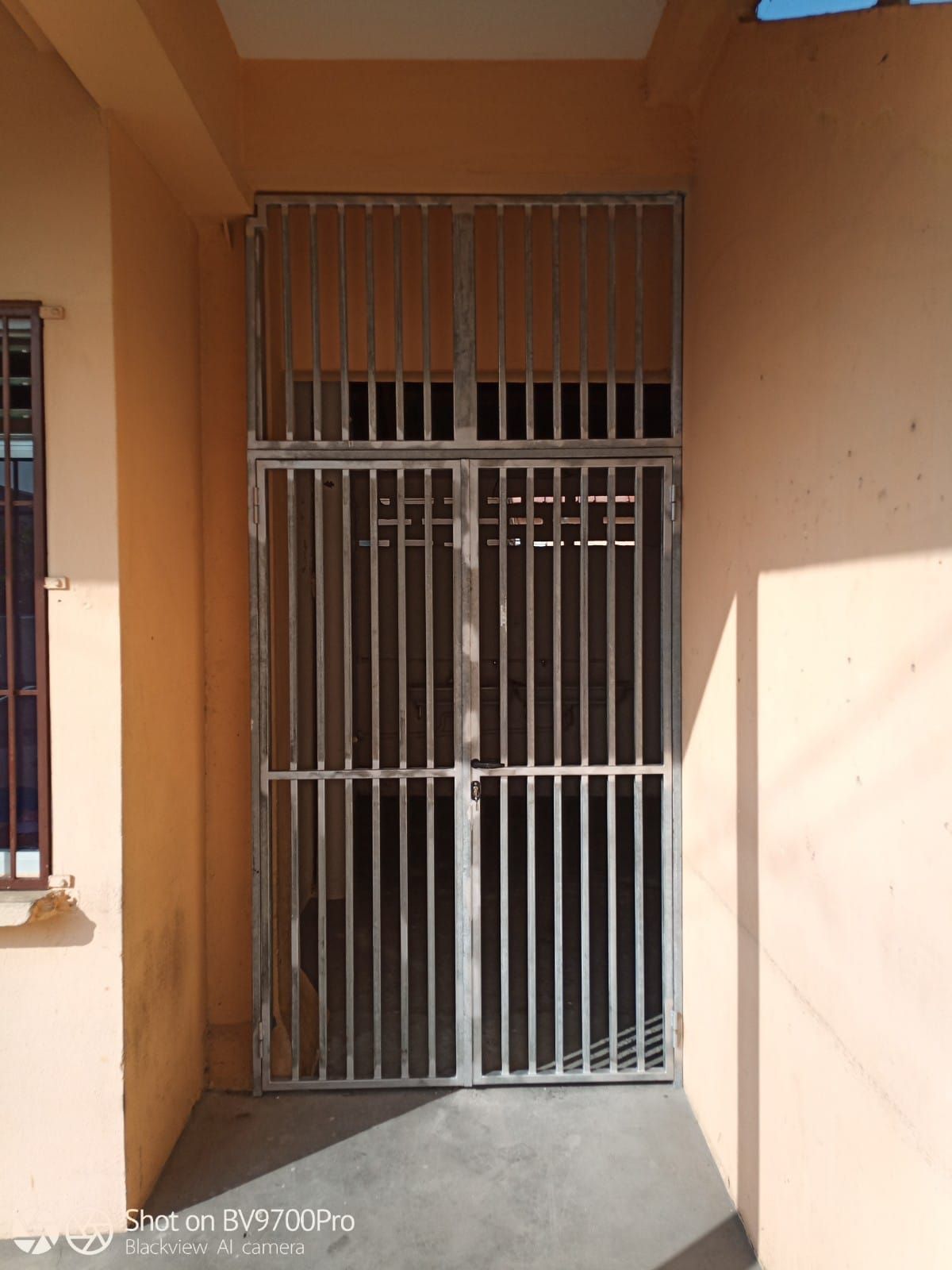 Une grille de sécurité métallique à barreaux verticaux.