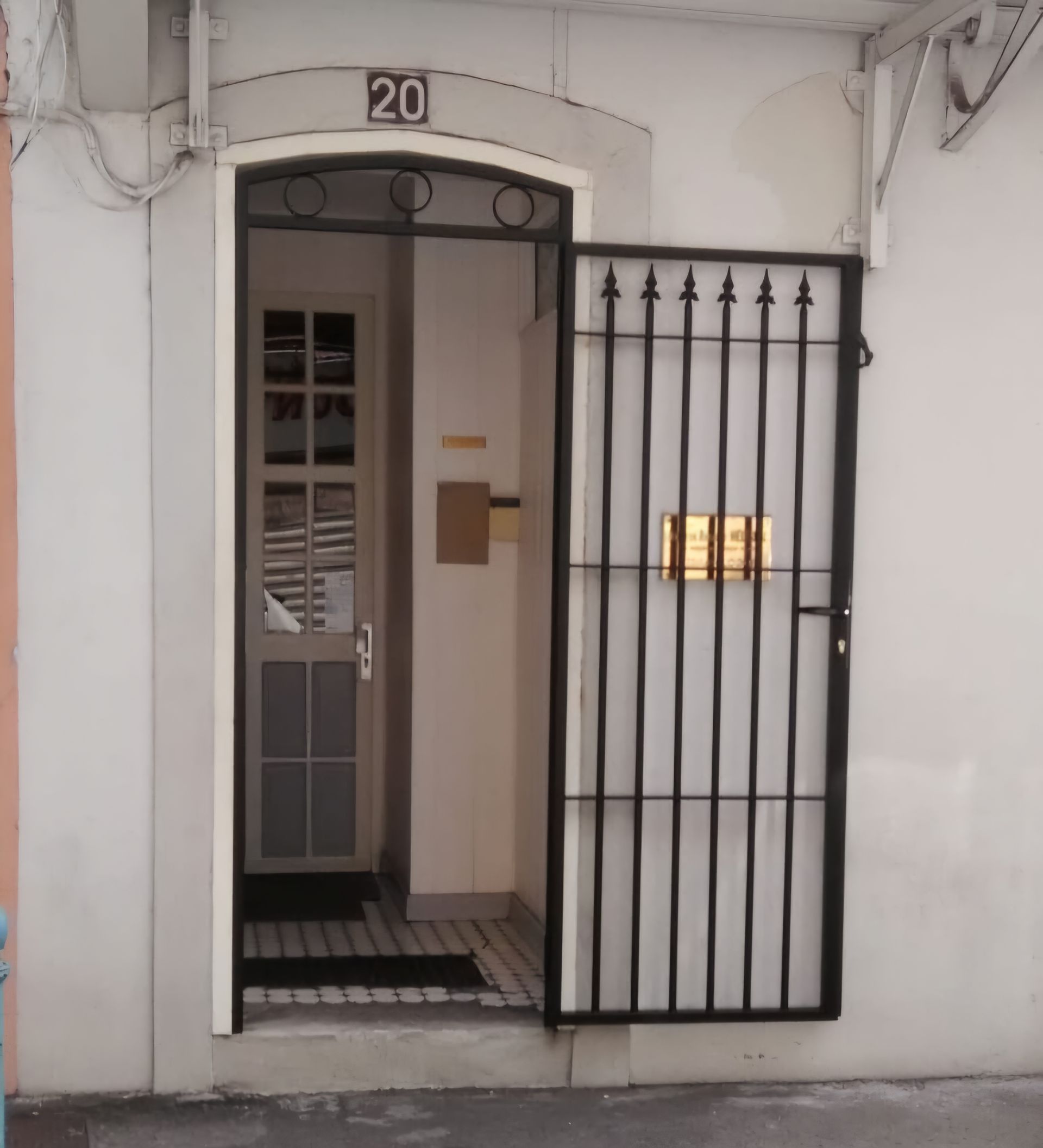 Une grille de sécurité ouverte en métal noir à l'entrée d'un bâtiment.