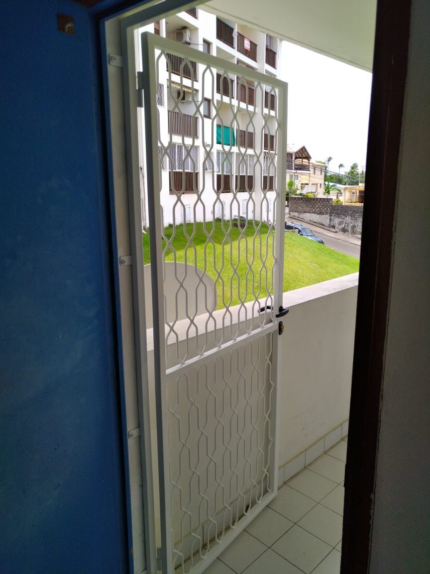 Une grille de protection en métal blanc à l'entrée d'un bâtiment.