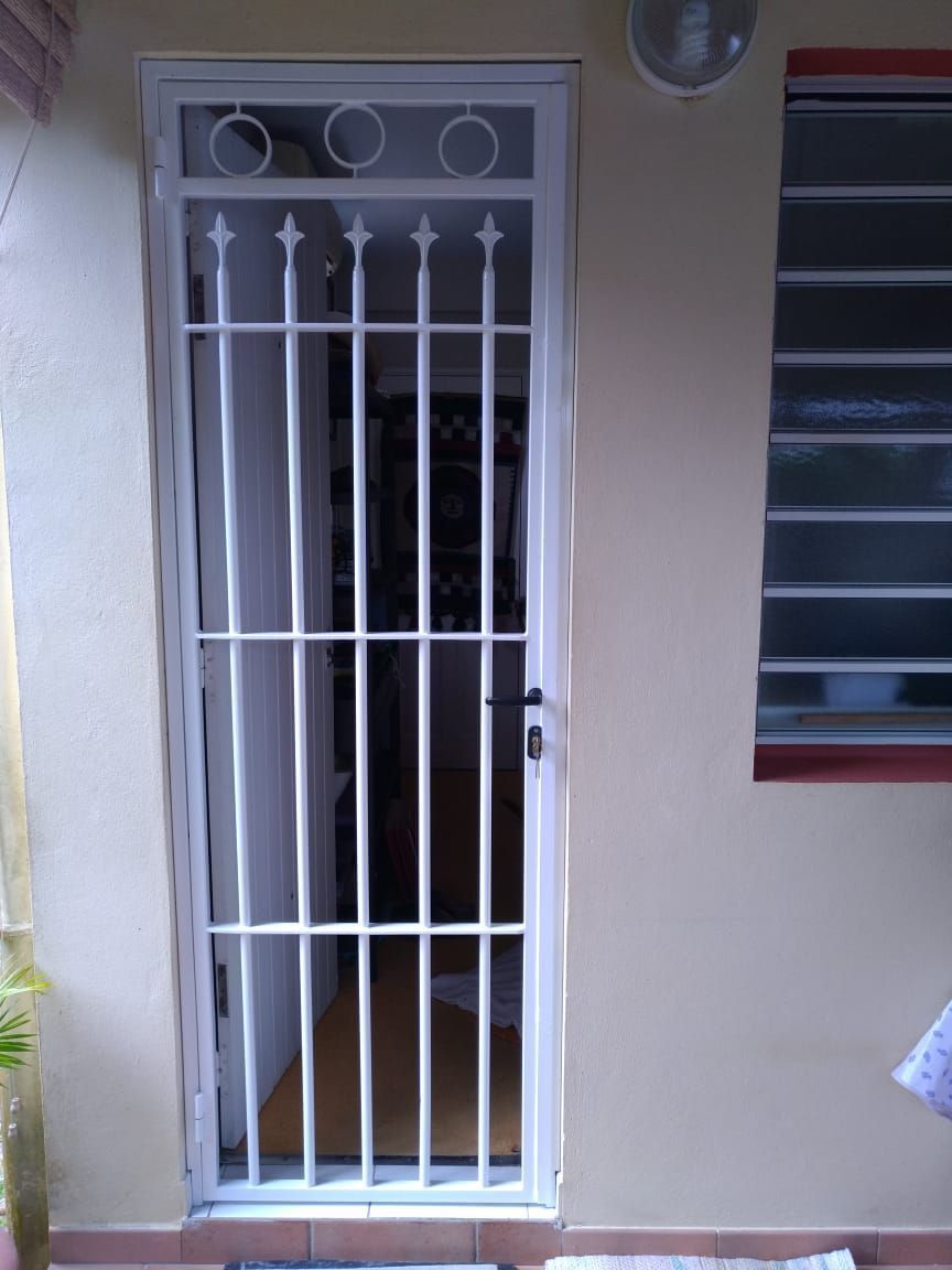 Grille de sécurité en métal blanc avec barre supérieure circulaire décorative et barreaux verticaux.