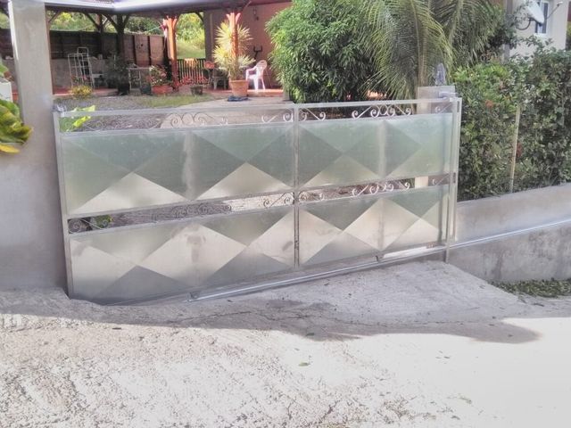 Un portail d'allée rectangulaire en métal argenté, orné d'un motif géométrique en losange.