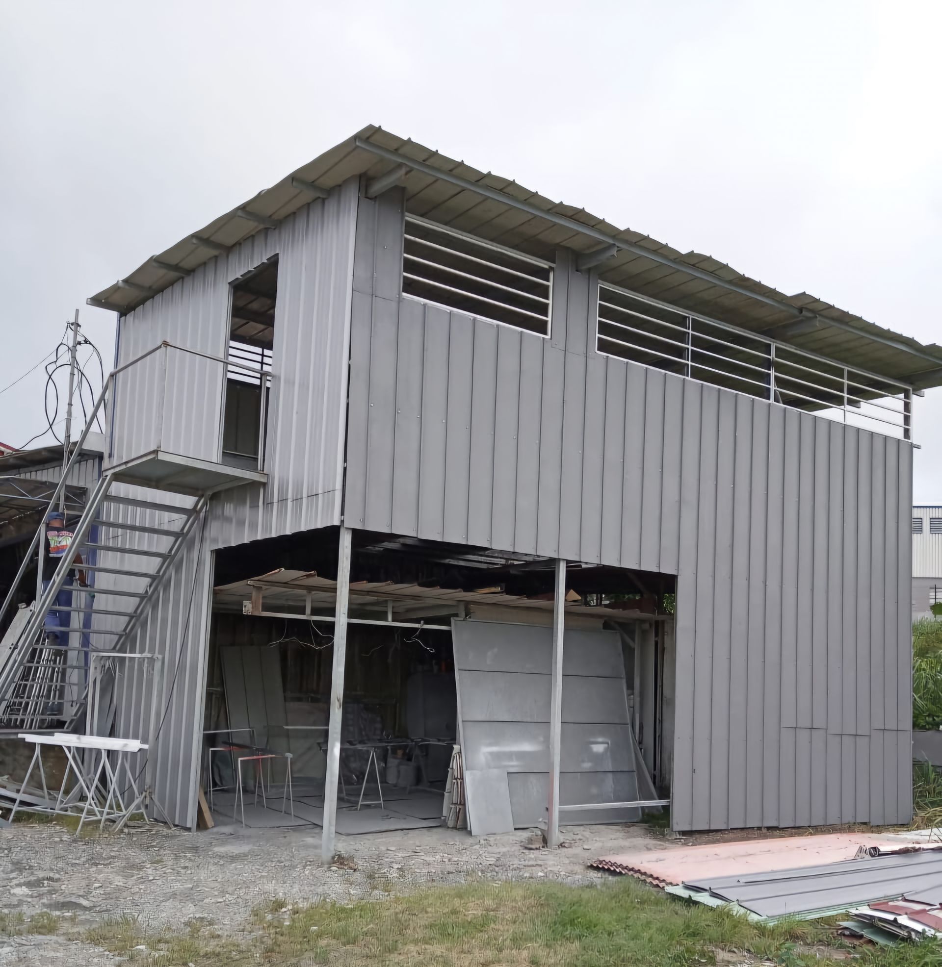 Une structure métallique grise ondulée à deux étages avec un escalier extérieur.
