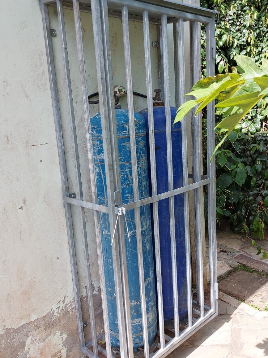 Deux grandes bonbonnes de gaz comprimé bleues sont rangées dans une cage métallique grise sécurisée.