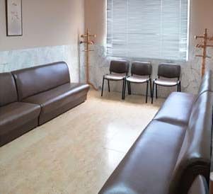 Una sala de espera con un sofá, sillas y una ventana.