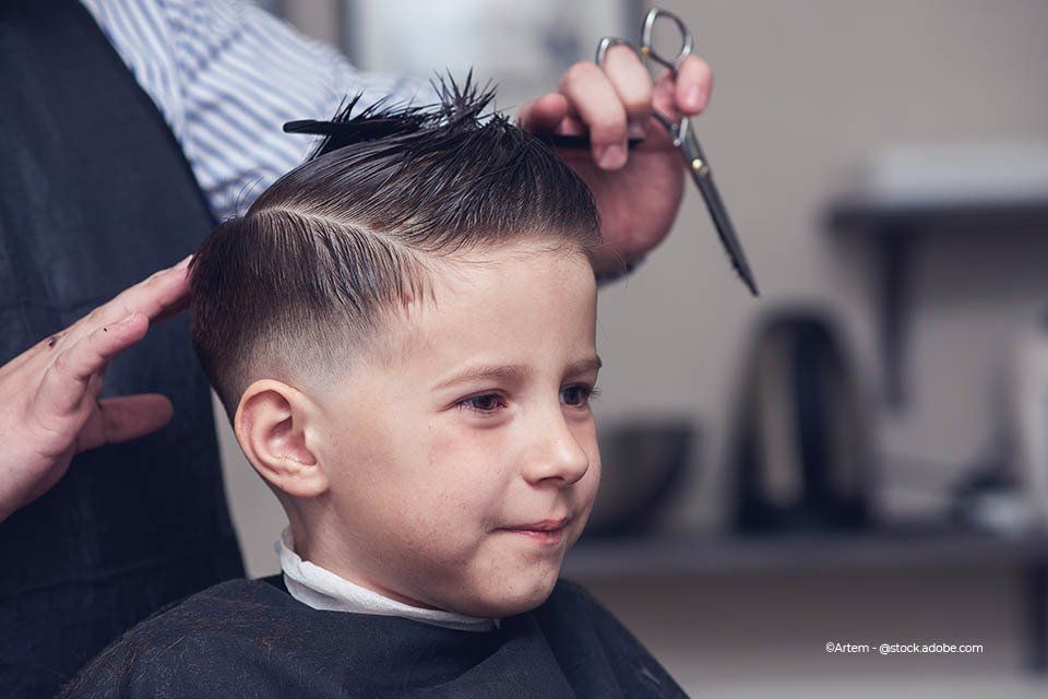 Mitarbeiterin von Haarstudio Dina schneidet die Haare eines Kindes