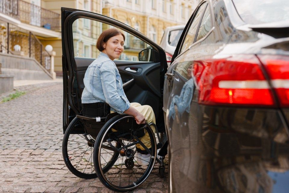 Person im Rollstuhl steigt in Pkw ein