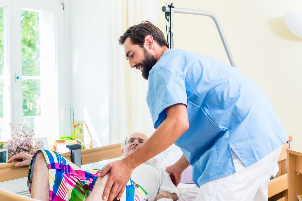 Eine Krankenschwester hilft einer älteren Frau in einem Krankenhausbett.