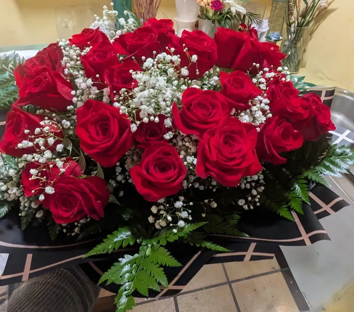 Ramo de rosas rojas con paniculata y follaje sobre una mesa.
