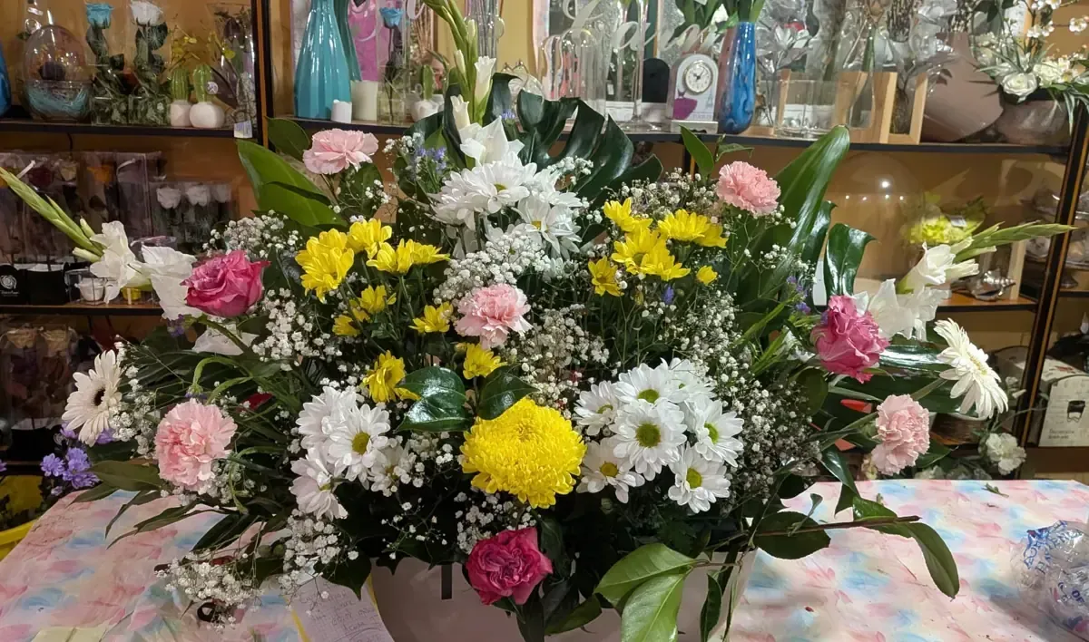 Un colorido ramo de flores rosas, amarillas y blancas dispuesto sobre una mesa en una tienda.