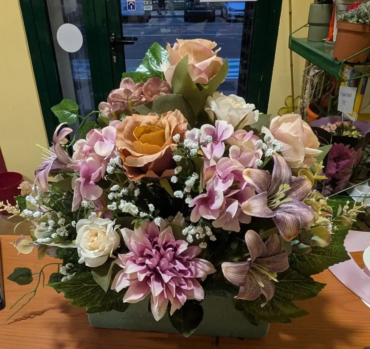 Variedad de flores en tonos pastel dispuestas en un ramo decorativo sobre una mesa en el interior.